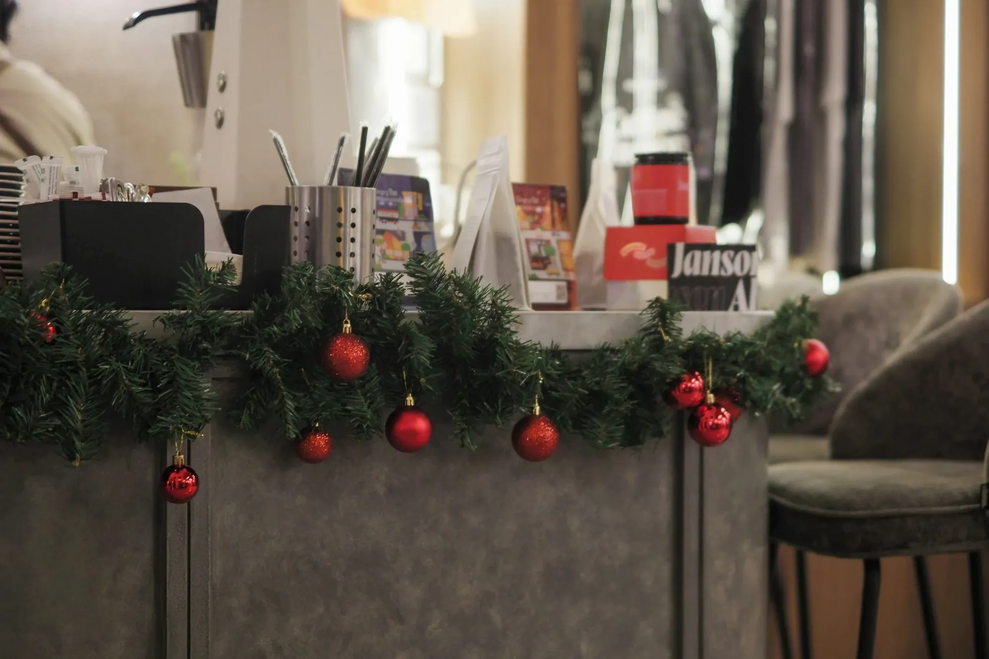 Pine garland with red ornaments draped along the front edge of a counter