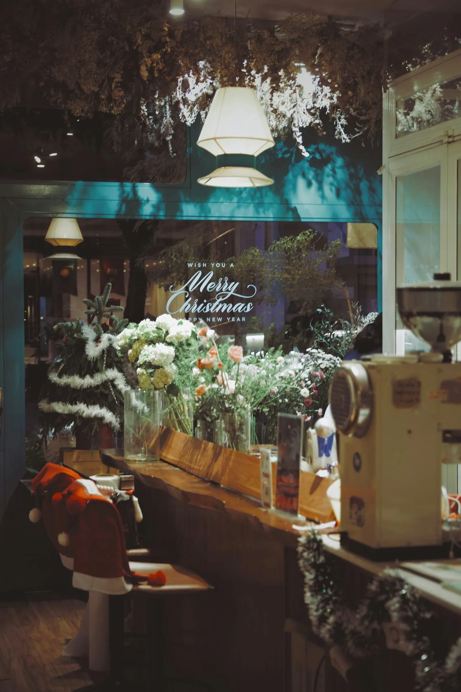 Coffee counter with white flowers, pine branches and fairy lights in front of a window