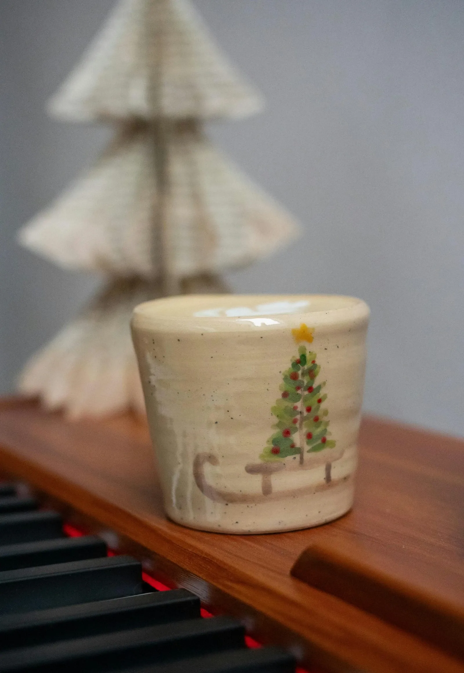 Ceramic mug painted with a small Christmas tree on a wooden table