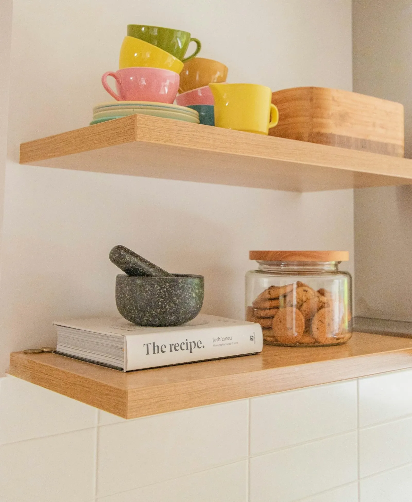 Floating shelves holding coffee mugs above a coffee bar