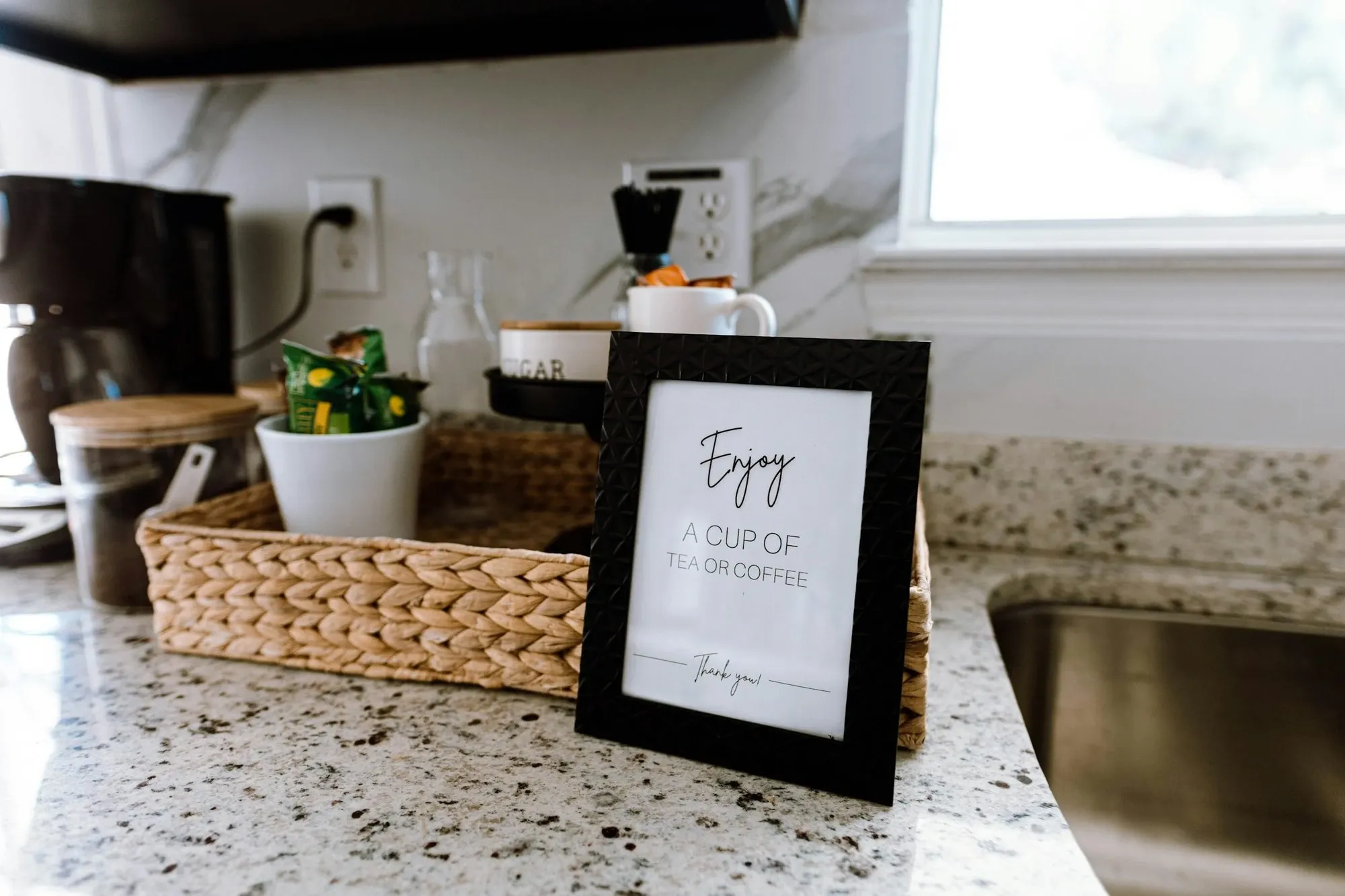 Tidy kitchen counter corner with a framed print and a woven tray, ready for a countertop coffee station