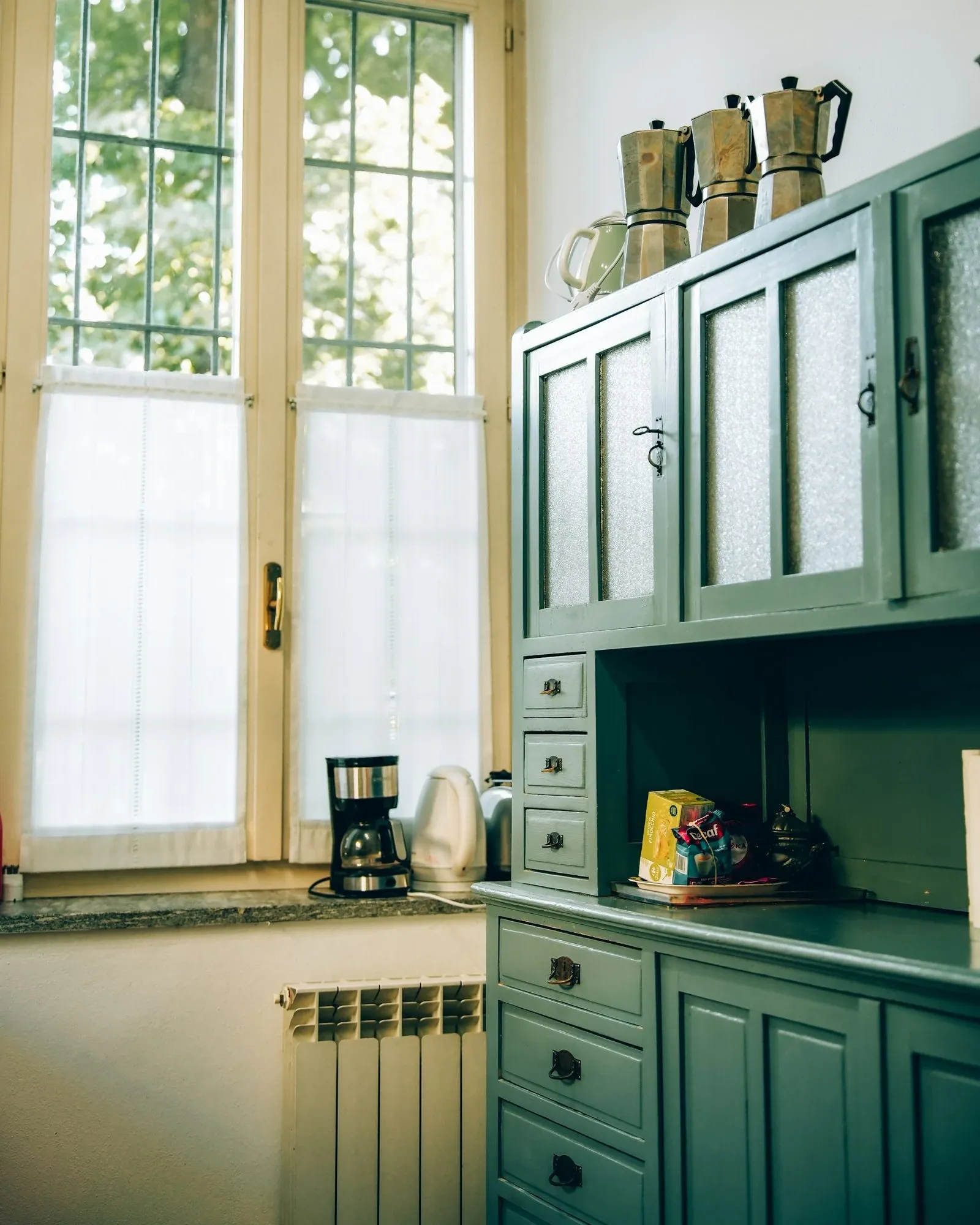Dark green hutch used as a coffee bar corner