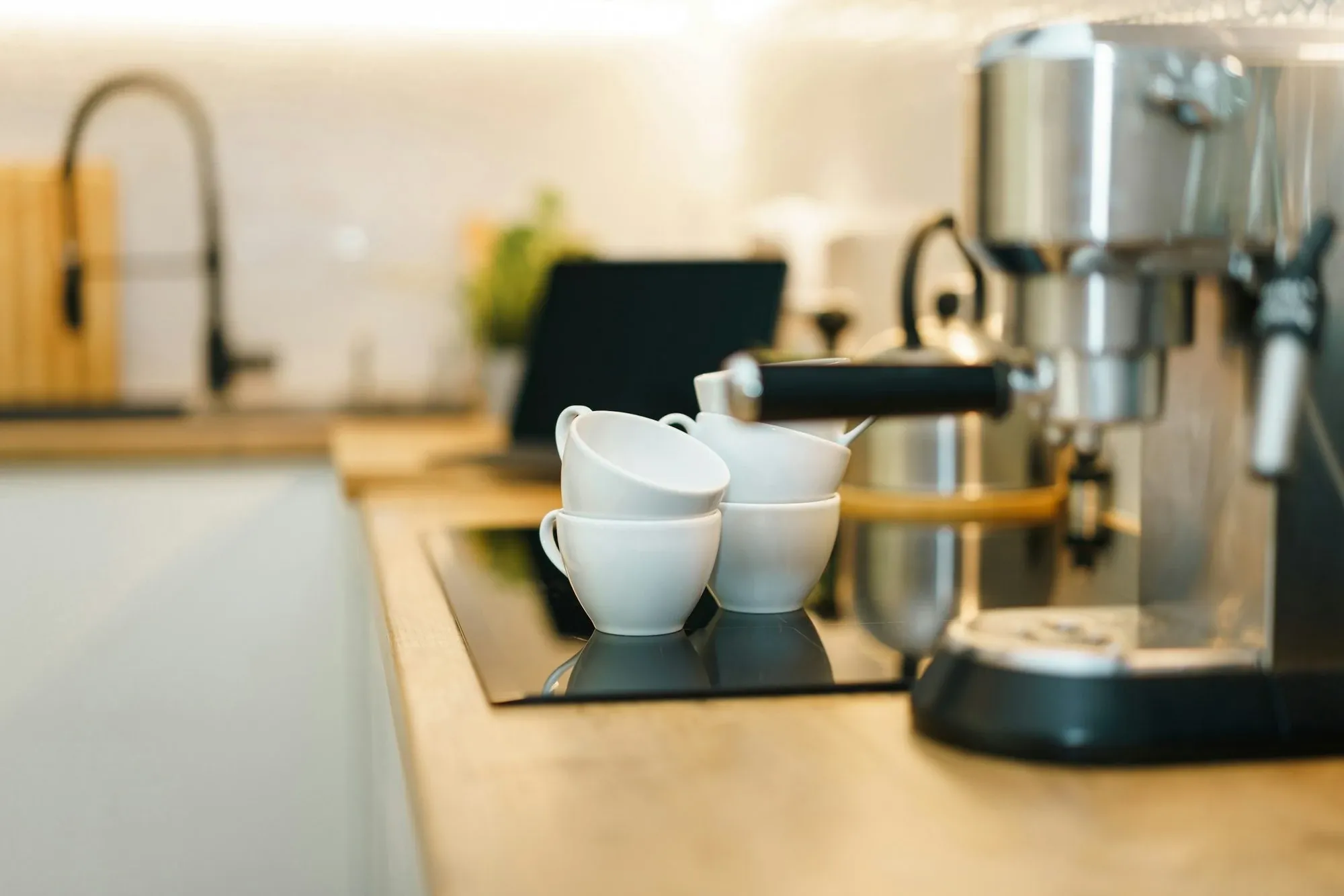 Home espresso machine on a kitchen counter with white cups