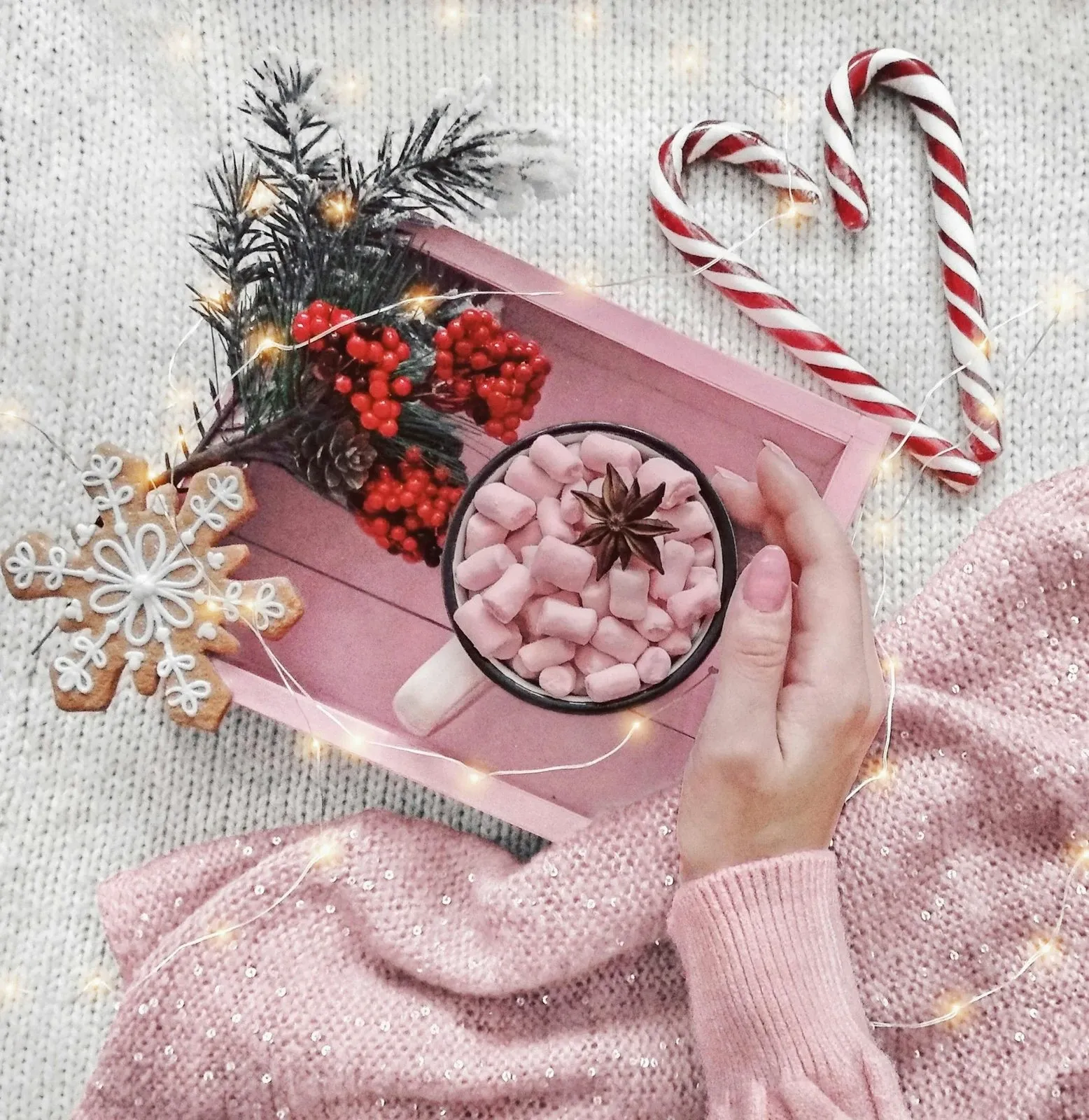 Pink tray with a mug of hot cocoa, pink marshmallows, candy canes, red berries and a pink knit sweater