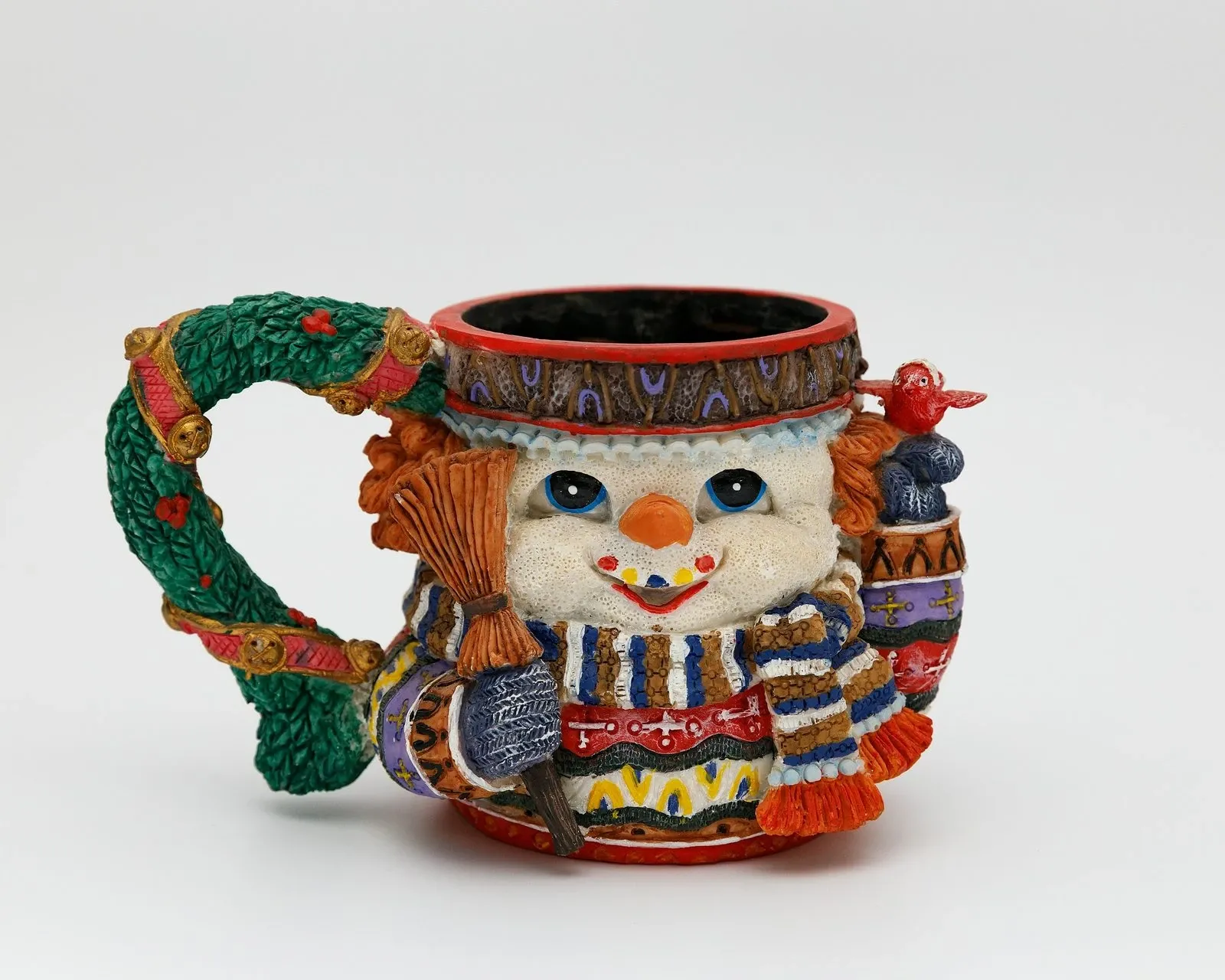 Ceramic snowman mug with a striped scarf and knit hat on a white background